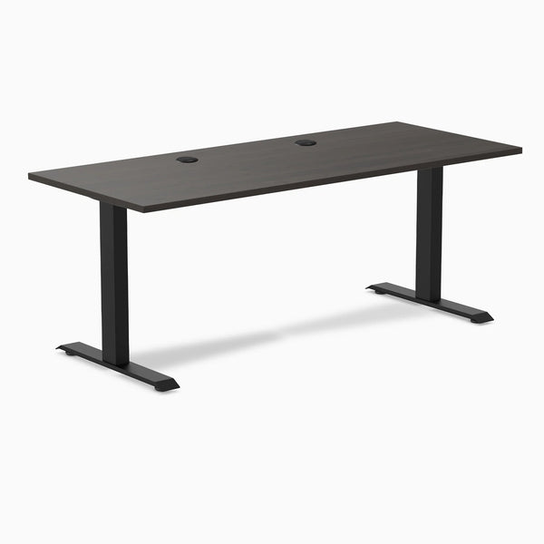 Desky Zero fixed-height office desk with burnished wood laminate top, two grommets, and matte black steel frame.