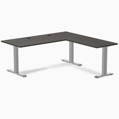 Burnished wood laminate L-shape office desk with gray steel frame and grommets.