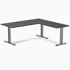 Burnished wood laminate L-shape office desk with space gray steel frame and grommets.