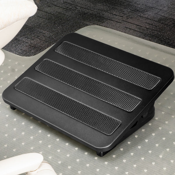 Black Desky Classic Foot Rest with three textured non-skid panels, on a clear mat over dark carpet.
