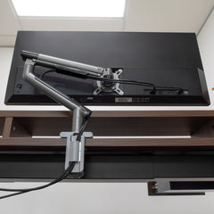 Desky Single Slim Aluminium Monitor Arm in space gray, mounted to a desk, supporting a black monitor.