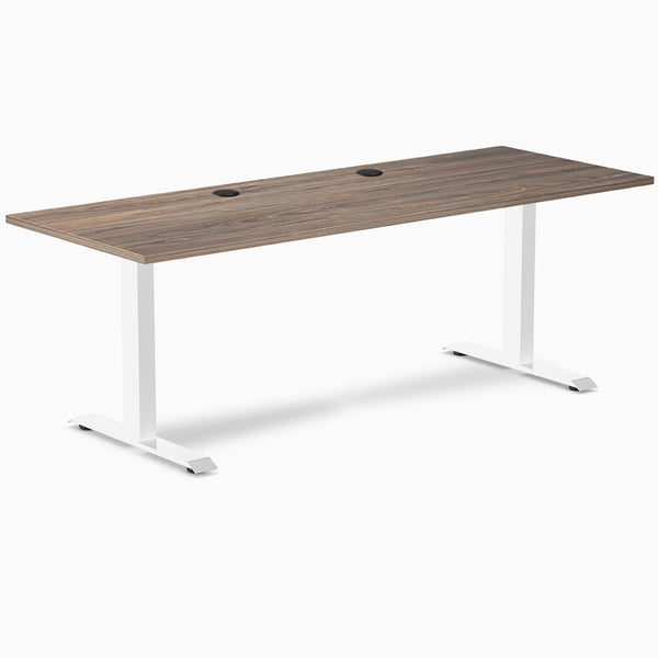 Desky Zero fixed-height office desk with natural walnut laminate top, white steel frame, and grommets.