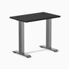 Desky Zero Mini fixed-height desk with black 32x20 inch top, grommets, and space gray legs.