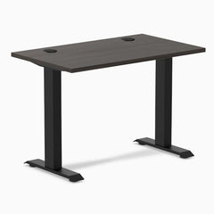 Desky Zero Mini sit-stand desk with burnished wood top, 40x24 inches, grommets, and matte black legs.