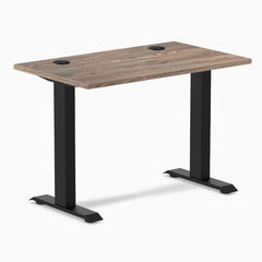 Desky Zero Mini sit-stand desk with natural walnut top, black fixed-height legs, and grommets.
