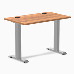 Desky Zero Mini fixed-height desk with Prime Oak top, gray legs, and two black grommets.