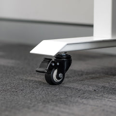 Black polyurethane locking caster wheel attached to a white steel desk leg on a gray carpet.