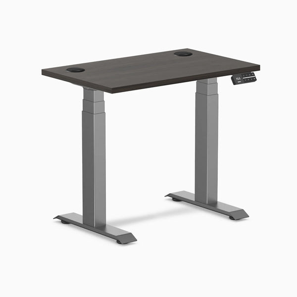 Desky Dual Mini sit-stand desk with burnished wood top, grommets, and space gray frame.