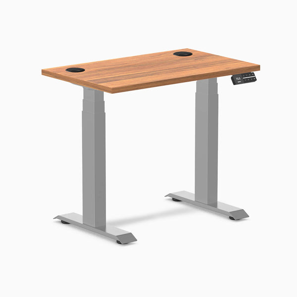 Desky Dual Mini sit-stand desk with Prime Oak top, gray frame, 32x20 inches, and grommets.