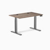 Desky Dual Laminate Sit Stand Desk in Natural Walnut, 47.2x29.5 inches, with grommets and Space Gray frame.