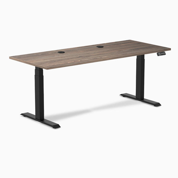 Desky Dual Sit Stand Desk with Natural Walnut laminate top, two grommets, and matte black frame.