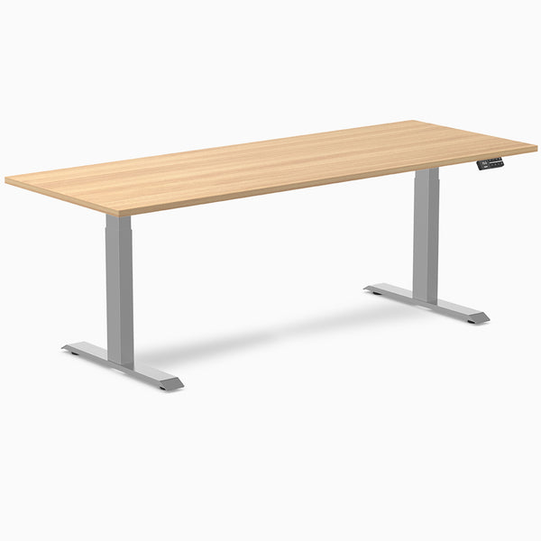 Desky Dual Custom Laminate Sit Stand Desk with light wood top and silver adjustable legs.